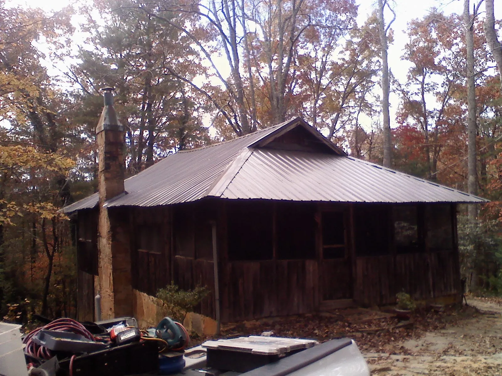 Brown metal hip roof on an old cabin with a stone chimney in Eaton