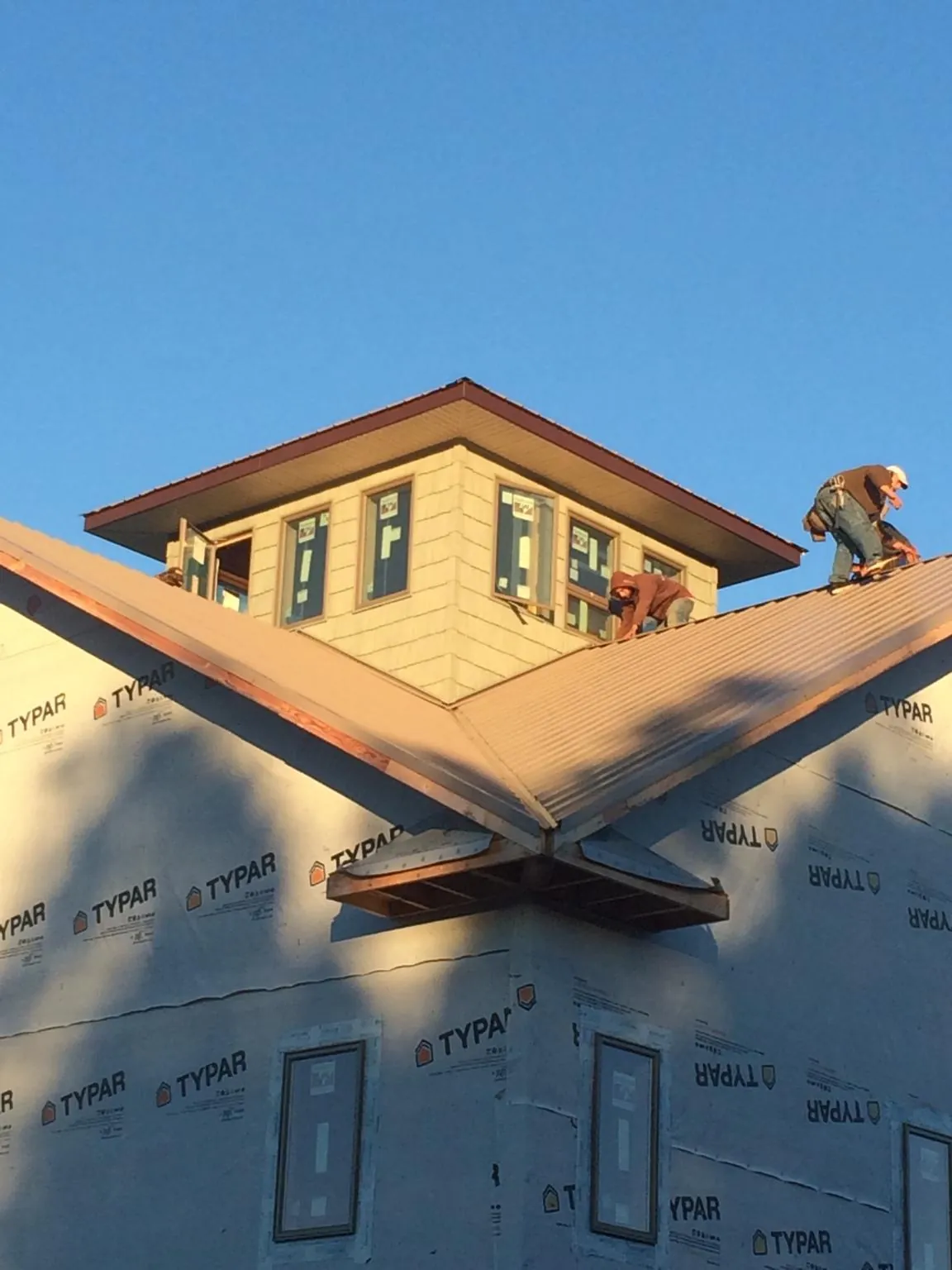 Roofers working around a rooftop cupola on a new metal roof at sunset — Roof Waterproofing in Eaton by Roofing Brothers